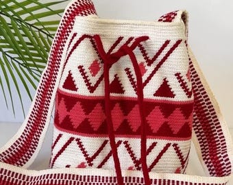 May include: Cream-colored woven bag with a geometric pattern in red. The bag has a drawstring closure and a wide strap, both with red accents. The text "This isn't just a bag" is visible on the image.