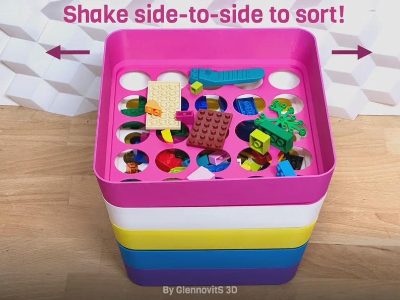 May include: A multi-colored plastic toy organizer with a pink top, white, yellow, blue, and purple base. The top has circular holes for sorting small toys. The text "Shake side-to-side to sort!" is above the organizer.