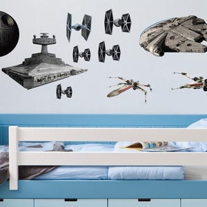 May include: Wall decals featuring iconic Star Wars spacecraft and structures, including the Death Star, a Star Destroyer, TIE fighters, X-wings, and the Millennium Falcon. The decals are displayed above a blue and white bed frame.