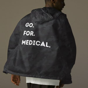 May include: Black camouflage jacket with a white hood and the text "GO. FOR. MEDICAL." printed on the back.