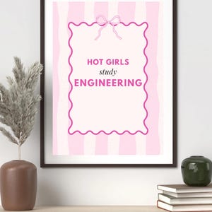 May include: A framed print with a pink and white striped background. The print features a pink scalloped border and a bow at the top. The text reads "HOT GIRLS study ENGINEERING" in pink lettering.