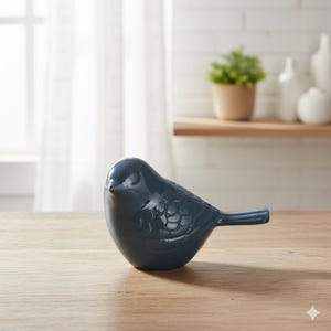 May include: A dark teal ceramic bird ornament with a glossy finish. The bird is positioned on a wooden surface, featuring detailed feather patterns. This decorative figurine is suitable for home decor.
