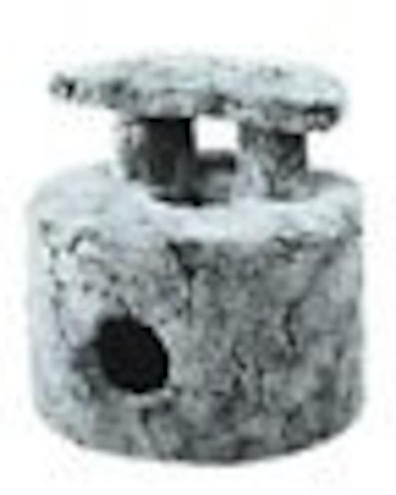 May include: A gray concrete aquarium ornament shaped like a small tower with a flat roof and a hole in the side. The tower has a small opening on the top.