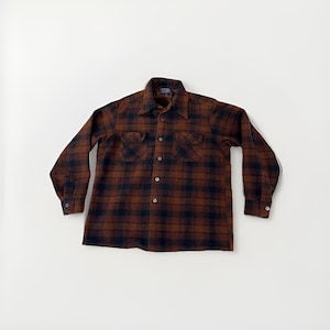 May include: A brown and navy check button-down shirt with two chest pockets. The long-sleeved shirt has a collared neckline and buttoned cuffs. The shirt is made of a soft, woven fabric.