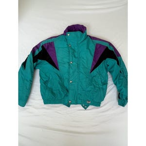May include: Teal, purple, and black vintage ski jacket. The jacket features a high collar, snap closures, and a ribbed hem. The sleeves have black accents and the shoulders have purple accents. A retro style winter coat.