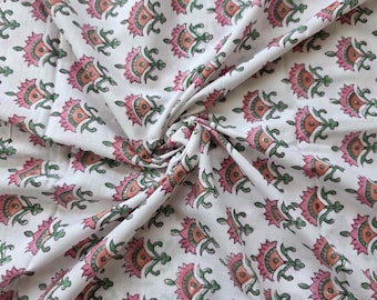May include: White fabric with a repeating floral pattern in pink, peach, and green. The flowers have a stylized design, and the fabric is folded, creating shadows and texture. The overall look is soft and feminine.