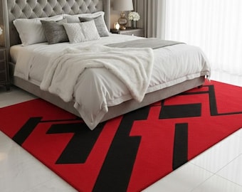 May include: A rectangular area rug featuring a vibrant red background with a bold, black geometric pattern consisting of thick, intersecting lines and angular shapes, positioned on a white tiled floor beneath a grey upholstered bed frame.