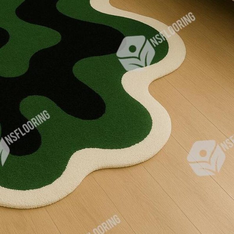 May include: A unique, abstract rug with a wavy, organic shape. The rug features a camouflage pattern in shades of green and black, with a cream-colored border. The rug is placed on a light-colored wooden floor.