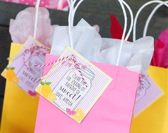 May include: Pink and yellow gift bags with white handles and tissue paper. The bags have tags that say "Thank you for making my birthday so sweet! Love Amelia" with a lemon and lemonade illustration.