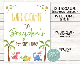 Op de afbeelding: Een printbaar welkomsbord voor een dinosaurusthema eerste verjaardag feest. Het bord heeft een groen welkomsbord met de tekst "Welkom bij Brayden's 1e verjaardag". Het bord is versierd met palmbomen en dinosaurussen in neutrale kleuren.