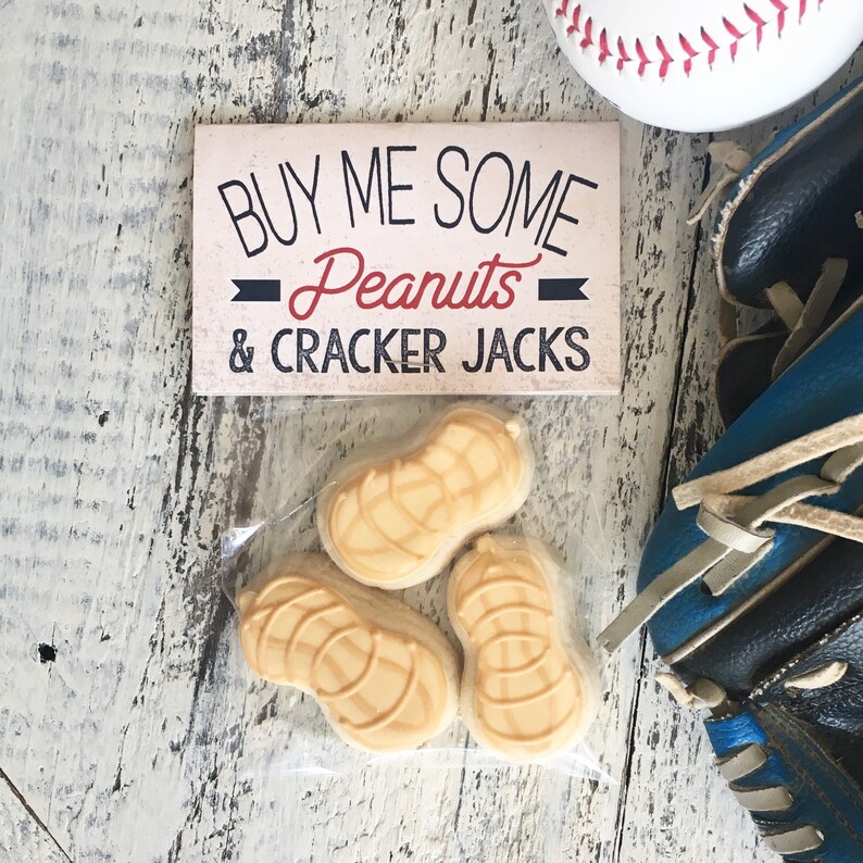 K&ouml;nnte beinhalten: Eine wei&szlig;e Karte mit schwarzem Text, auf der "Buy me some Peanuts & Cracker Jacks" steht. Drei erdnussf&ouml;rmige Kekse befinden sich in einem durchsichtigen Plastikbeutel.