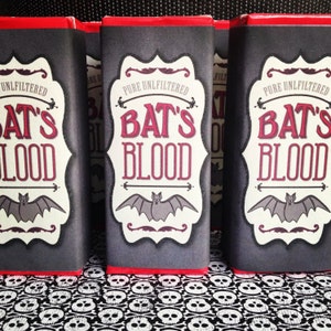 May include: Three black and white chocolate bar wrappers with red trim. Each wrapper has a white label with a bat graphic and the text "Pure Unfiltered Bat's Blood".