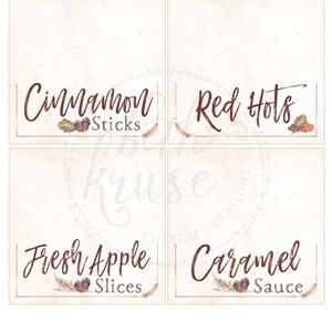 May include: Four printable tent cards with fall-themed designs. The cards feature the text "Cinnamon Sticks", "Red Hots", "Fresh Apple Slices", and "Caramel Sauce".