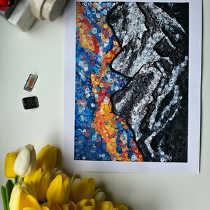 May include: Abstract art print featuring a profile in grayscale against a vibrant background of blue, orange, and yellow swirls. The artwork is on white paper, with a bouquet of yellow and white tulips in the foreground. Decorative ladybug and stone magnets are also present.