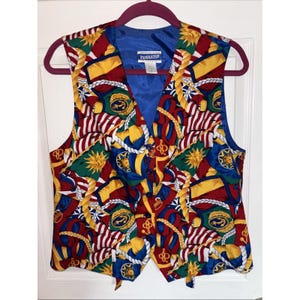 May include: A colorful Pendleton vest with a vibrant pattern of flags, suns, and nautical elements in red, yellow, blue, and green. The vest has a blue lining and a button-up front. The vest is hanging on a pink hanger.