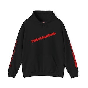 May include: Black hoodie with a front pocket and a hood. The hoodie features the red text "#WeTheMob" across the chest and "#WeTheMob" down the sleeves.
