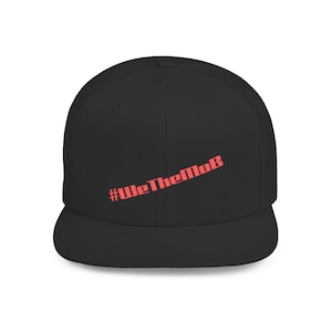 May include: Black baseball cap with a flat brim. The cap features the red text "#WeTheMob" diagonally across the front. The cap is a solid black color.