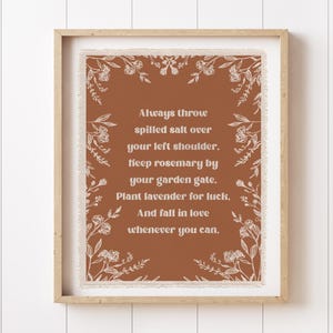 May include: A framed print with a brown background and white text that reads, "Always throw spilled salt over your left shoulder. Keep rosemary by your garden gate. Plant lavender for luck. And fall in love whenever you can."
