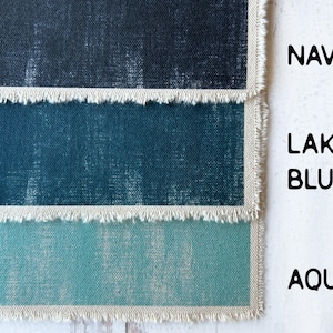 May include: Close-up of three fabric swatches in navy, lake blue, and aqua. Each swatch has a frayed edge and is labelled with its respective colour name in a bold font. The fabrics have a textured appearance.