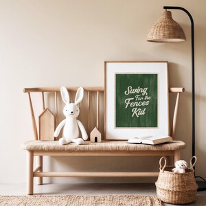 May include: A light-toned interior scene with a wooden bench, a framed print reading "Swing for the Fences Kid", and a soft toy rabbit. A woven basket and a floor lamp add to the room's decor.