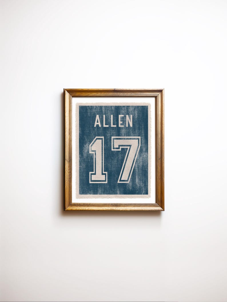 May include: Framed print featuring the name "ALLEN" above the number "17" in a vintage style. The text and numbers are white against a blue background, with a distressed texture. The frame is a warm brown color.