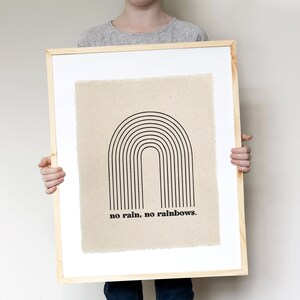 May include: A framed print with a black and white illustration of a rainbow on a beige background. The text "no rain, no rainbows." is printed below the rainbow.