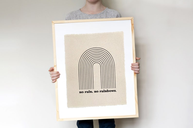 May include: A framed print with a black and white illustration of a rainbow on a beige background. The text "no rain, no rainbows." is printed below the rainbow.