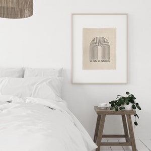 May include: A framed print with a black and white illustration of a rainbow with the text "no rain, no rainbows." The print is hanging on a white wall above a wooden nightstand with a potted plant and a white cup.