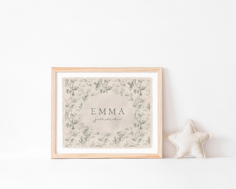 May include: A framed print with a beige background and a green floral pattern. The print has the name "Emma June" in a cursive font.