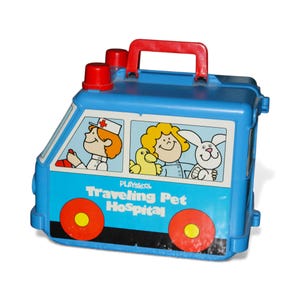 May include: A blue Playskool Traveling Pet Hospital toy. The toy ambulance has red wheels, a red handle, and two red lights. The side of the toy features illustrations of a nurse, a child, a duck, and a rabbit.