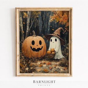 May include: A framed art print featuring a large orange jack-o'-lantern with a carved face next to a white ghost wearing a brown witch hat and holding a small woven basket filled with orange pumpkins in a dark forest with fallen autumn leaves.