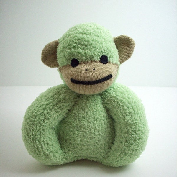 Un jouet de bébé singe chaussette en vert et beige