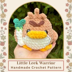 Peut inclure: Un jouet en crochet représentant un oiseau rond marron avec un ventre blanc, un bec et des pattes jaunes. Il possède des sourcils marron foncé et tient un poireau blanc et vert. Le texte indique Little Leek Warrior Handmade Crochet Pattern @LittleYarnPals.