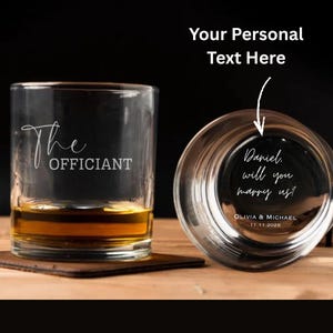 Puede incluir: Dos vasos de whisky transparentes, uno en posición vertical con el texto "The Officiant", el otro invertido con el texto "Daniel, will you marry us!". Los vasos están sobre una superficie de madera, con un fondo oscuro. También es visible la fecha 11.11.2026.