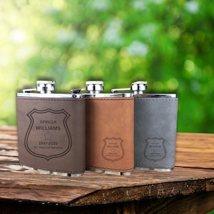 May include: Three personalized flasks in brown, tan, and gray leather. Each flask has a silver cap and is engraved with a police badge design, the name "OFFICER WILLIAMS", and the text "1997-2025 30 Years of Service".