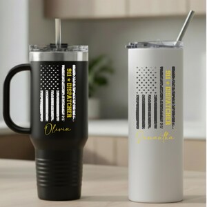 May include: Two insulated tumblers, one black and one white, each featuring a distressed American flag design. The black tumbler has a handle and the name "Olivia" in gold script. The white tumbler has the name "Samantha". Both have "911 DISPATCHER" text.