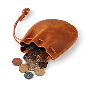 May include: A brown leather coin purse with a drawstring closure and wooden bead detail. The purse is open, spilling out a collection of various coins. The leather has a distressed appearance.