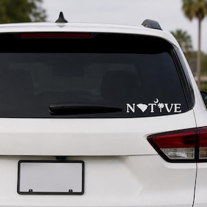 May include: A white vinyl decal applied to the rear window of a white vehicle. The decal features the text "NATIVE" in a bold, sans-serif font, with the letter "A" replaced by the silhouette of South Carolina and the "I" replaced by a palmetto tree.
