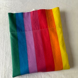 Pode incluir: Um tecido listrado arco-íris dobrado com uma costura branca no meio.