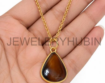May include: A gold-toned necklace featuring a teardrop-shaped brown gemstone pendant set in a smooth gold-colored bezel. The pendant hangs from a delicate gold-toned cable chain. The text JEWELRYHUBIN is overlaid across the center of the image.