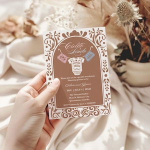 May include: A gender reveal party invitation with a brown and white design. The invitation features the text "Cielito Lindo" and includes details about the event, such as the date, time, and location. Decorative floral elements frame the text.