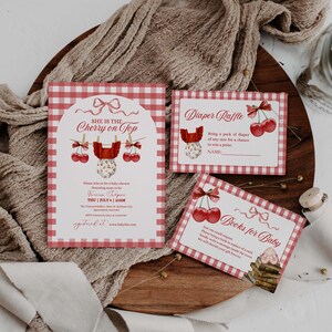 May include: Baby shower invitation and cards with a red and white gingham pattern. The invitation reads "She is the Cherry on Top" with cherry and baby clothes illustrations. Cards include "Diaper Raffle" and "Books for Baby".