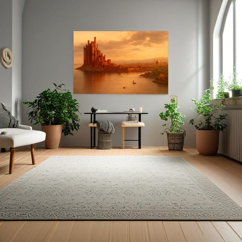 May include: A large framed canvas art print depicting a sunset over a coastal city with a prominent castle. The artwork is displayed in a modern living room setting with plants, a rug, and a minimalist desk.