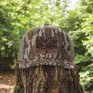 Puede incluir: Gorra de camionero de camuflaje con un parche marrón con el texto "Chasing Thunder" y un gráfico de una tormenta. La gorra tiene una parte trasera de malla y una visera curva. La gorra está sobre un tocón de árbol.