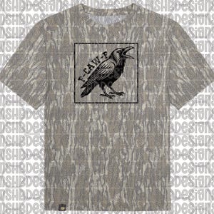 May include: A t-shirt with a camouflage pattern, displaying a black raven illustration inside a black square. The raven has an open beak, and the text "F-CAW-F" is above it. The shirt has short sleeves and a crew neck.
