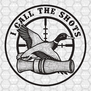 May include: Black and white graphic design featuring a duck in flight, centered within a rifle scope. The text "I CALL THE SHOTS" is in a circular arrangement around the scope. The design is suitable for apparel or accessories.