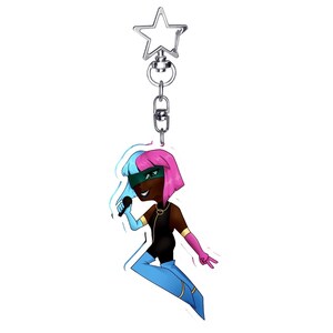 May include: A cartoon keychain featuring a character with pink and blue hair, a green mask, and a black outfit. The character is holding a microphone and is attached to a silver star-shaped keychain.
