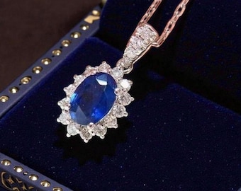 May include: A necklace featuring an oval-shaped deep blue gemstone surrounded by a halo of small, clear, round-cut stones. The pendant is attached to a delicate metallic chain, with the entire piece showcasing a classic, elegant design.