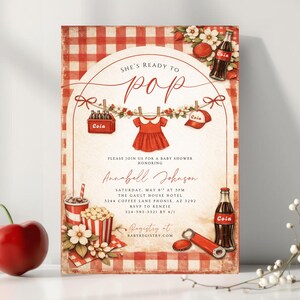 May include: A vintage-style baby shower invitation with a red and white checkered background. The invitation features the text "She's Ready to Pop" and includes illustrations of a baby dress, cola bottles, and popcorn. The invitation also includes the name Annabell Johnson.