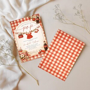 May include: Baby shower invitation with a red and white gingham pattern. The invitation features the text "She's Ready to Pop" and includes illustrations of baby clothes, popcorn, and soda bottles.
